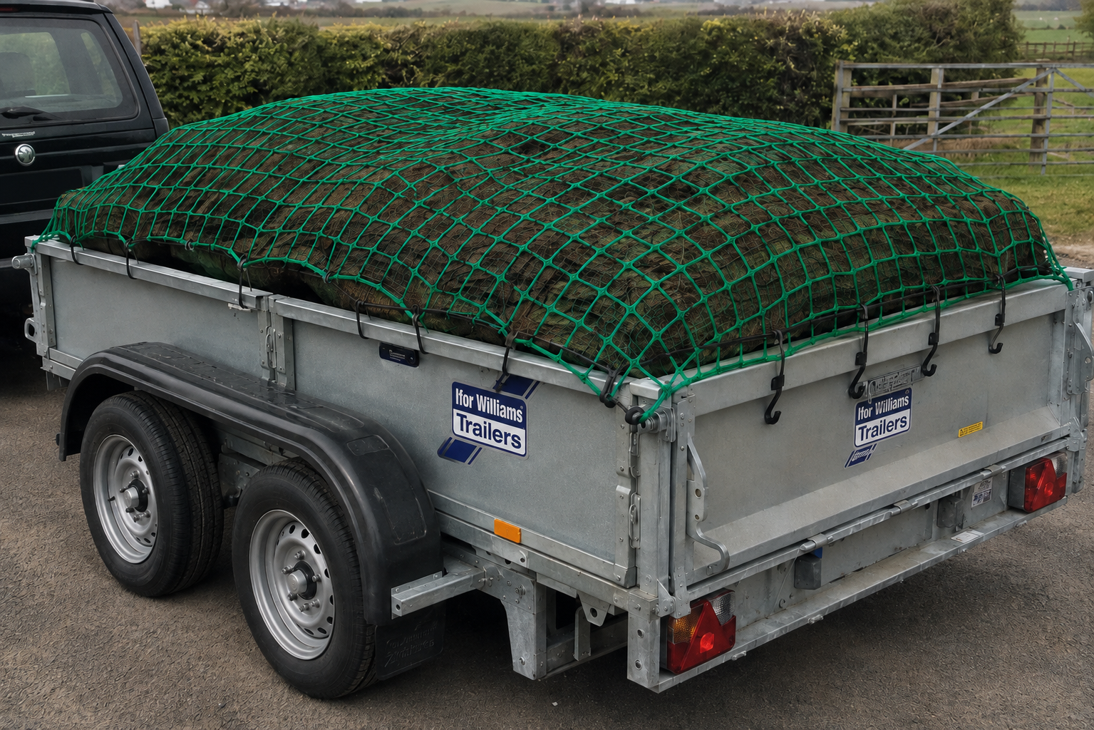 Black cargo net with blue bungee edging secured over a trailer load